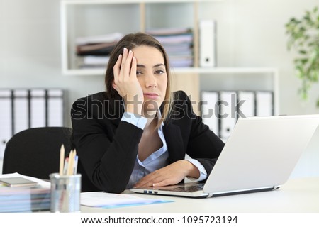 Frustrated executive posing looking at camera on a desktop at office
