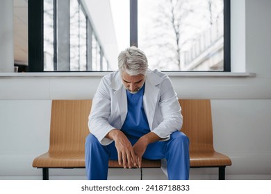 Frustrated, exhausted doctor sitting on bench in hospital corridor. Concept of burnout syndrome among doctors. - Powered by Shutterstock