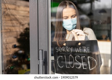 Frustrated Female Cafe Or Store Owner Wearing Medical Mask Hangs A Sign Board With An Inscription Sorry We Are Closed, Small Business Lockdown Due To Coronavirus, Bankrout Concept