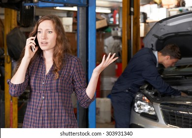 Frustrated Female Customer On Mobile Phone At Auto Repair Shop