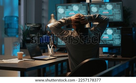 Frustrated hacker using computer to break into corporate data servers, working under pressure. Infecting software system with dangerous network virus, stealing security information. Tripod shot.