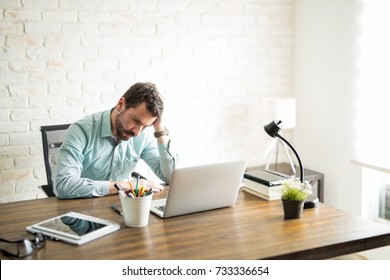 Frustrated Independent Business Owner Sitting With A Hand On His Head And A Worried Look