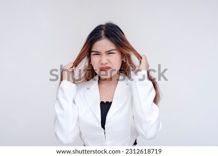 A frustrated and irritated young woman pulling her hair with both hands in annoyance. Clearly agitated and cracking under pressure. Isolated on a white background.
