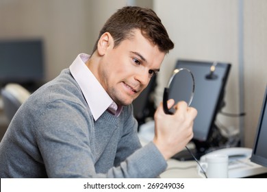 Frustrated Male Customer Service Representative Holding Headphones In Office