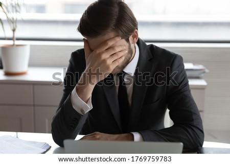 Frustrated male employee sit at desk work on laptop feel stressed with company bankruptcy news, disappointed businessman distressed disappointed with corporate business failure or money loss Foto stock © 