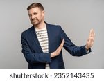 Frustrated man with disgust on serious face incredulously pushes away troubles with gesture of hands isolated on gray background. Male with angry expression refuse something bad showing denial.