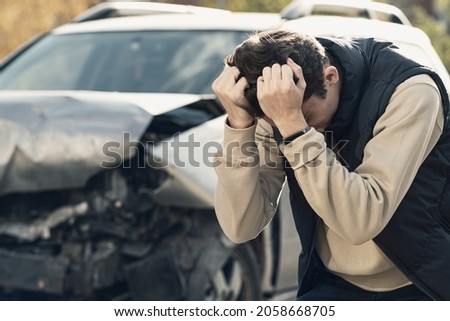 A frustrated man near a broken car. Grabbed my head realizing the damage is serious, the car is beyond repair