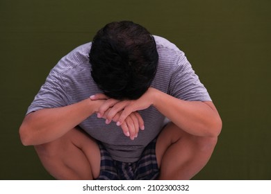 Frustrated Man Squatting With Head Facing Down