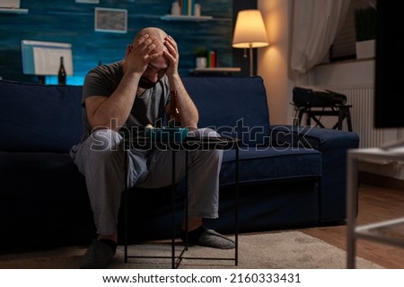 Frustrated man watching sports on television program and feeling sad about football team losing championship game. Soccer supporter fan feeling upset and emotional about match defeat.