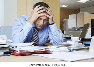 Frustrated middle aged businessman sitting at office desk - Powered by Shutterstock