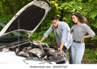 Frustrated Middle-eastern Couple Having Broken Car While Countryside Trip, Puzzled Arab Guy And Lady Checking Engine, Sad Mixed Race Family Stuck In The Middle Of Road, Trying To Fix Auto