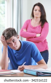 Frustrated Mother Watching Teenage Son Doing Homework