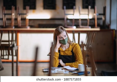 Frustrated owner sitting at table in closed cafe, small business lockdown due to coronavirus. - Shutterstock ID 1887571855