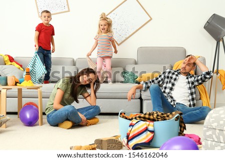 Frustrated parents and their mischievous children in messy room