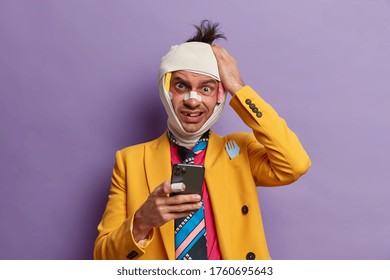 Frustrated Puzzled Man Takes Revenge From Someone, Keeps Hand On Head, Gets Strange Message On Cellular, Doesnt Know What To Answer, Has Bandaged Head, Broken Teeth, Isolated On Purple Background