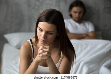 Frustrated sad girlfriend sit on bed think of relationship problems, thoughtful couple after quarrel lost in thoughts, upset lovers consider break up, offended person disappointed by boyfriend 