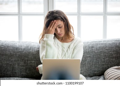 Frustrated sad woman feeling tired worried about problem sitting on sofa with laptop, stressed depressed girl troubled with reading bad news online, email notification about debt or negative message - Shutterstock ID 1100199107