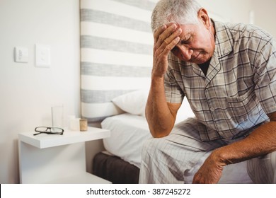 Frustrated Senior Man Sitting On Bed In Bedroom