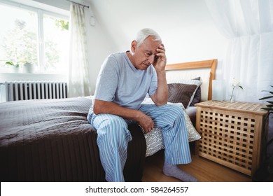 Frustrated senior man sitting on bed in bedroom - Powered by Shutterstock