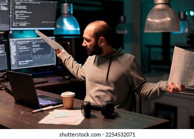 Frustrated software developer working late at night, feeling under pressure to meet deadline. Using html script and terminal window to program source code, being overworked and stressed. - Powered by Shutterstock