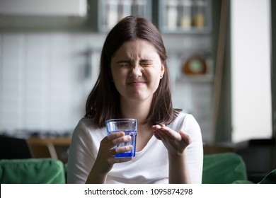 Frustrated Stressed Young Woman Grimacing Afraid Of Taking Pill Holding Glass Of Water, Teen Girl Does Not Like Daily Supplements Or Prescribed Medication, Fear Of Medicine Side Effects Concept