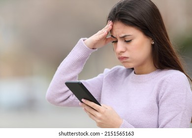 Frustrated teen checking smart phone content standing in the street - Powered by Shutterstock