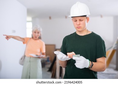 Frustrated Teenager Workman Having Construction Internship On Summer Vacation, Holding Money. Dissatisfied Female Customer Gesturing On Background