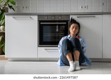 Frustrated tired worried Asian woman feeling frustrated about mortgage default lack of money and debt. Upset female suffering from bad relationship problem while sadly sits on floor with smartphone. 