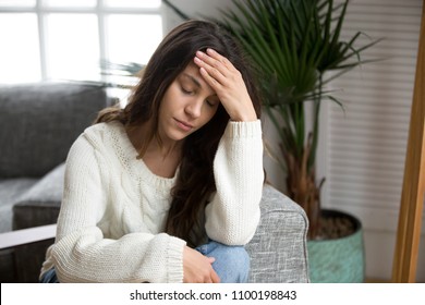 Frustrated tired young woman feeling strong headache touching forehead, depressed upset girl suffering from migraine, stressed worried teenager experiencing sudden panic attack or anxiety at home - Shutterstock ID 1100198843