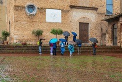 Frustrierte Touristen Im Regen Mit Regenschirmen, Die Die Sehenswürdigkeiten Von San Gimignano In Italien Sehen