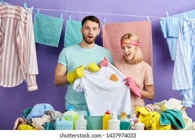 Frustrated Unhappy Couple Holding White T-shirt With A Spot On It. Close Up Portrait. Lifestyle, Job, Profession, Occupation. Laundry