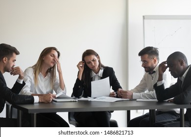 Frustrated upset multiracial business team people sad with bad work result in report disappointed in corporate bankruptcy failure crisis worried of paperwork problem sit at table at office meeting