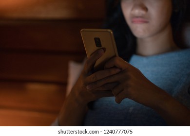 Frustrated Upset Woman Lying In Bed Looking At Smart Phone At Night