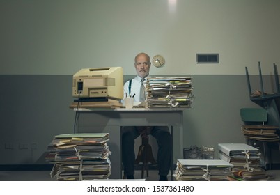 Frustrated vintage style businessman working in a rundown old office space, he is overloaded with papework
