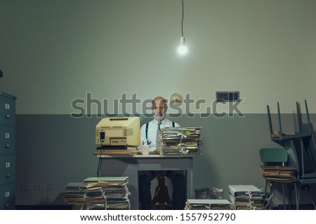 Frustrated vintage style businessman working in a rundown  office, he is overloaded with papework