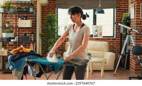 Frustrated woman ironing clothes and being angry at husband, wife needing help with household chores. Stressed tired person cleaning house and doing housekeeping work without man. - Shutterstock ID 2297640767