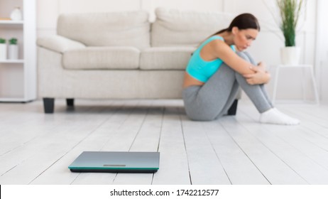 Frustrated Woman Sitting Near Weight Scales After Unsuccessful Mass Loss At Home, Focus On Weight-Scales. Selective Focus, Panorama