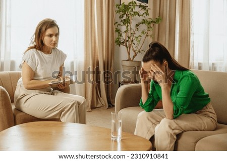 Frustrated woman sitting at psychologist's therapist appointment and telling about her problems.
