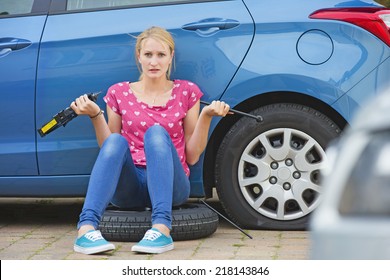 Frustrated Woman Trying To Change Flat Tire On Car