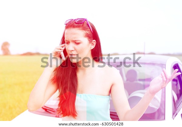 Frustrated
woman using cell phone against broken down
car