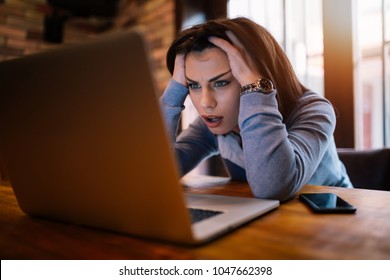 Frustrated worried young woman looks at laptop upset by bad news, teenager feels shocked afraid reading negative bullying message, stressed girl troubled with problem online or email notification.