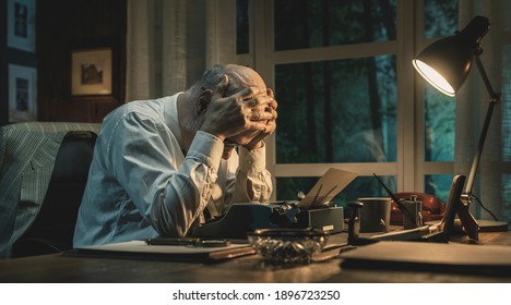 Frustrated writer experiencing a creative slowdown, he is sitting at desk and typing on a vintage typewriter