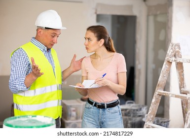 Frustrated Young Adult Female Designer Arguing With Male Worker While Examining Indoor Construction Site At Renovating Object