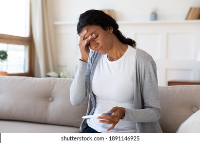 Frustrated Young African American Woman Looking At Pregnancy Test, Feeling Stressed Of Unwanted Results. Unhappy Millennial Multiracial Lady Holding Ovulation Stick, Upset With Infertility At Home.