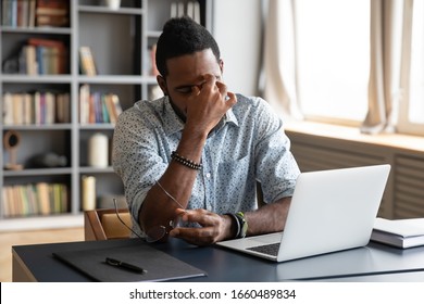 Frustrated young biracial guy taking off eyeglasses, massaging nose bridge, feeling tired due to computer overwork. Overwhelmed stressed millennial african american man suffering from eyes strain. - Shutterstock ID 1660489834
