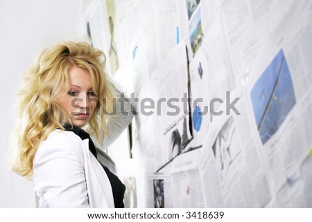a frustrated young businesswoman against a wall with a lot of newspapers