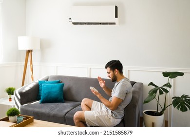 Frustrated young man feeling worried about the broken air conditioner and remote control 