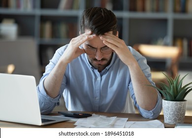 Frustrated young man in glasses sitting at table, feeling stressed calculating earnings or domestic expenses. Unhappy millennial guy suffering from lack of money, banking debt bankruptcy concept. - Powered by Shutterstock