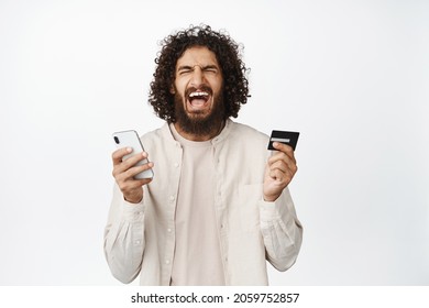 Frustrated Young Man Screaming, Holding Mobile Phone And Credit Card, No Money, Not Enough Funds On Account, White Background