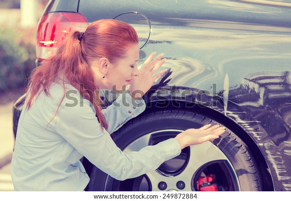Frustrated young woman checking pointing at car\
scratches and dents outdoors outside\
